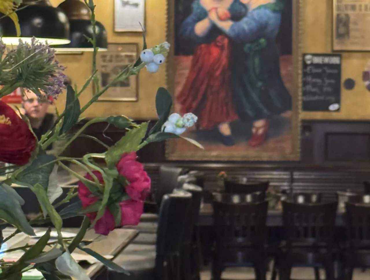 Wandschildering van de twee zusjes met verse bloemen in het café van Zusjes de Boer