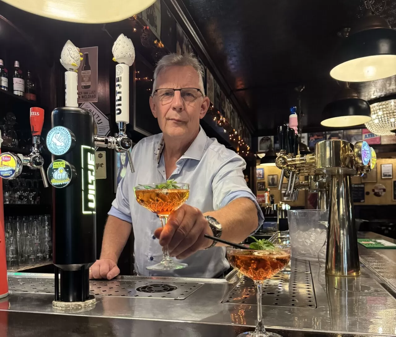 Een van de eigenaren van Zusjes de Boer serveert twee cocktails aan de bar