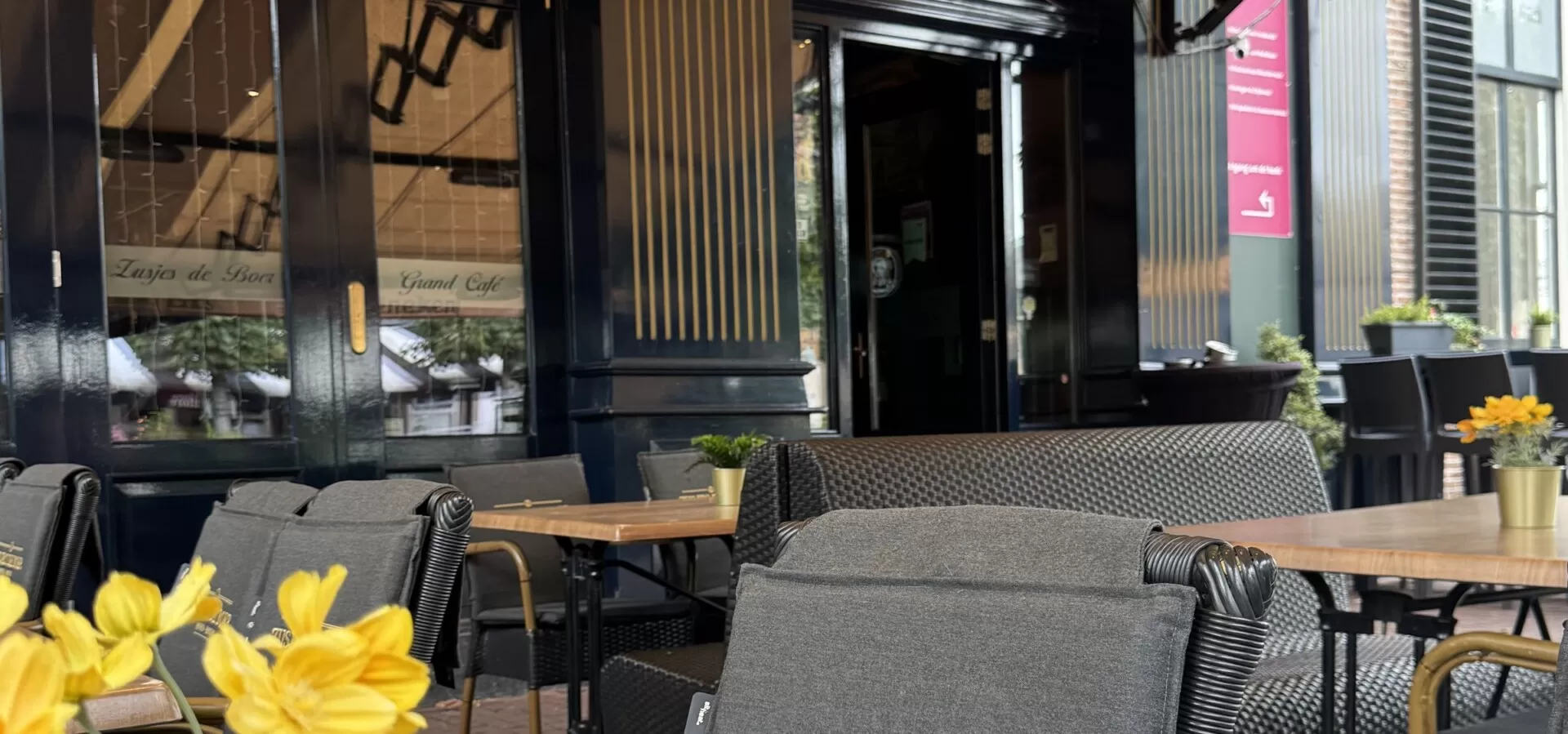 Terrastafel met gele bloemen voor de gevel van Zusjes de Boer