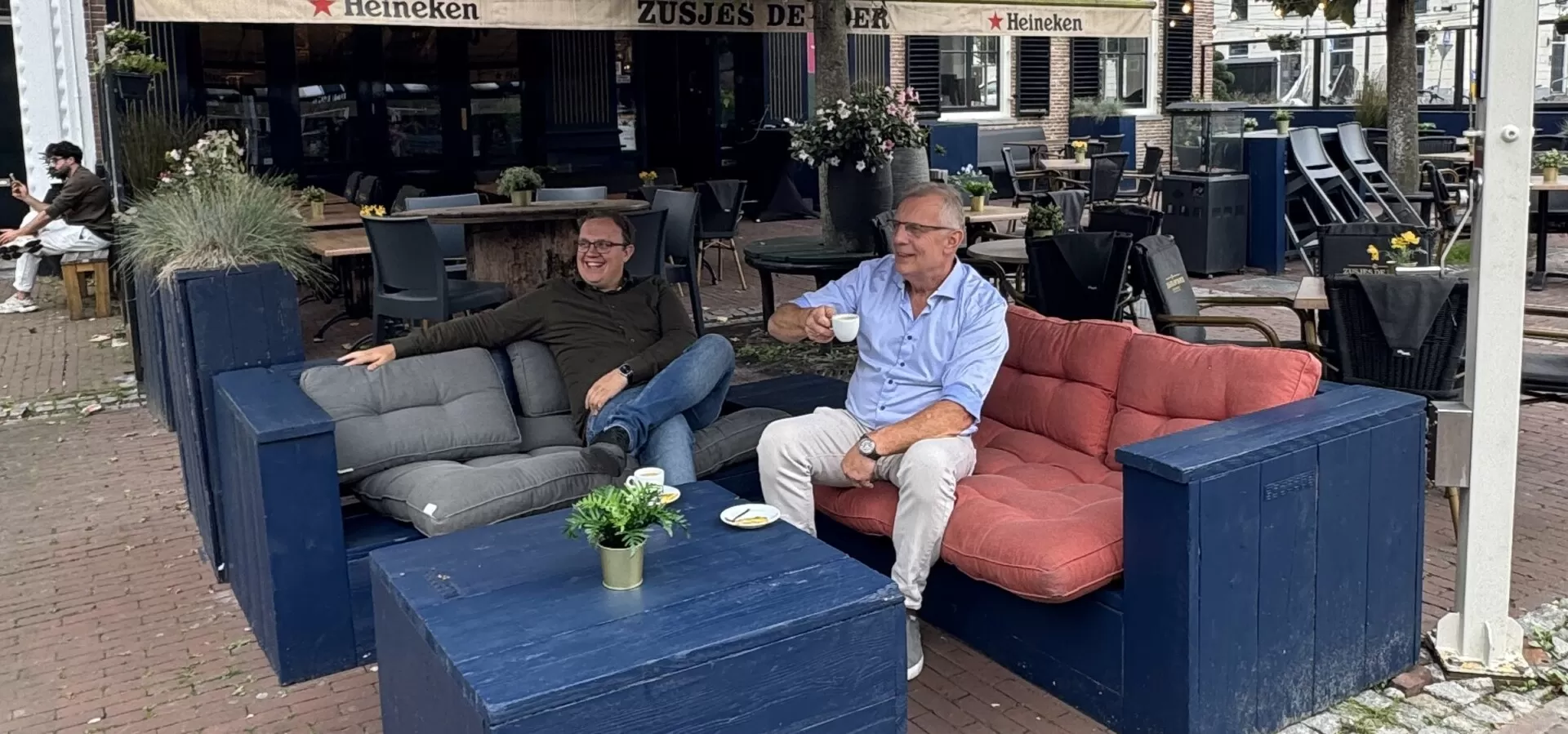De eigenaren van Zusjes de Boer ontspannen op het terras onder de grote parasol